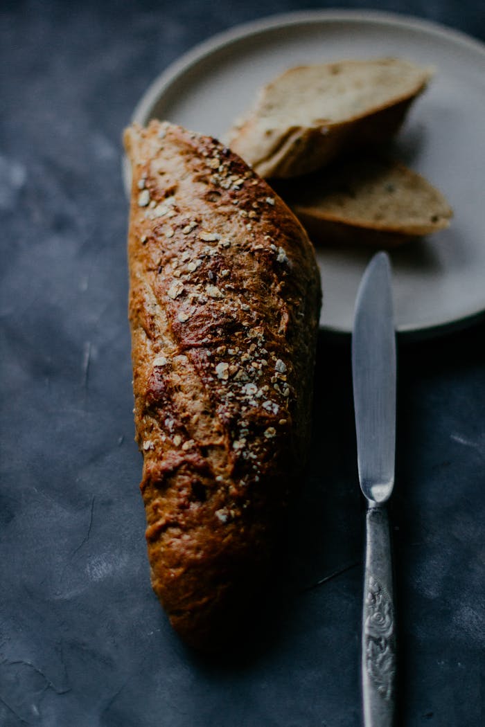 Close-up of freshly baked whole grain bread and knife on a plate for a rustic meal.