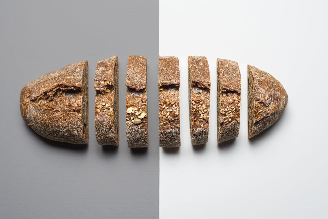 Flat lay of sliced artisan bread on contrasting gray and white backgrounds.