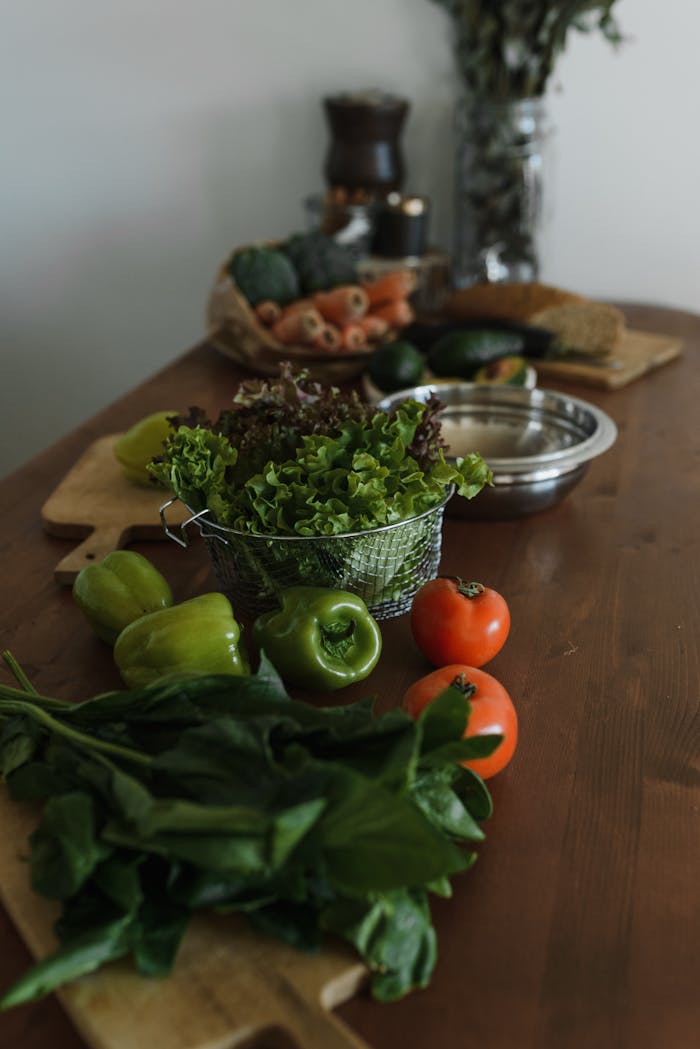 A selection of fresh vegetables including tomatoes, lettuce, and peppers on a wooden table.